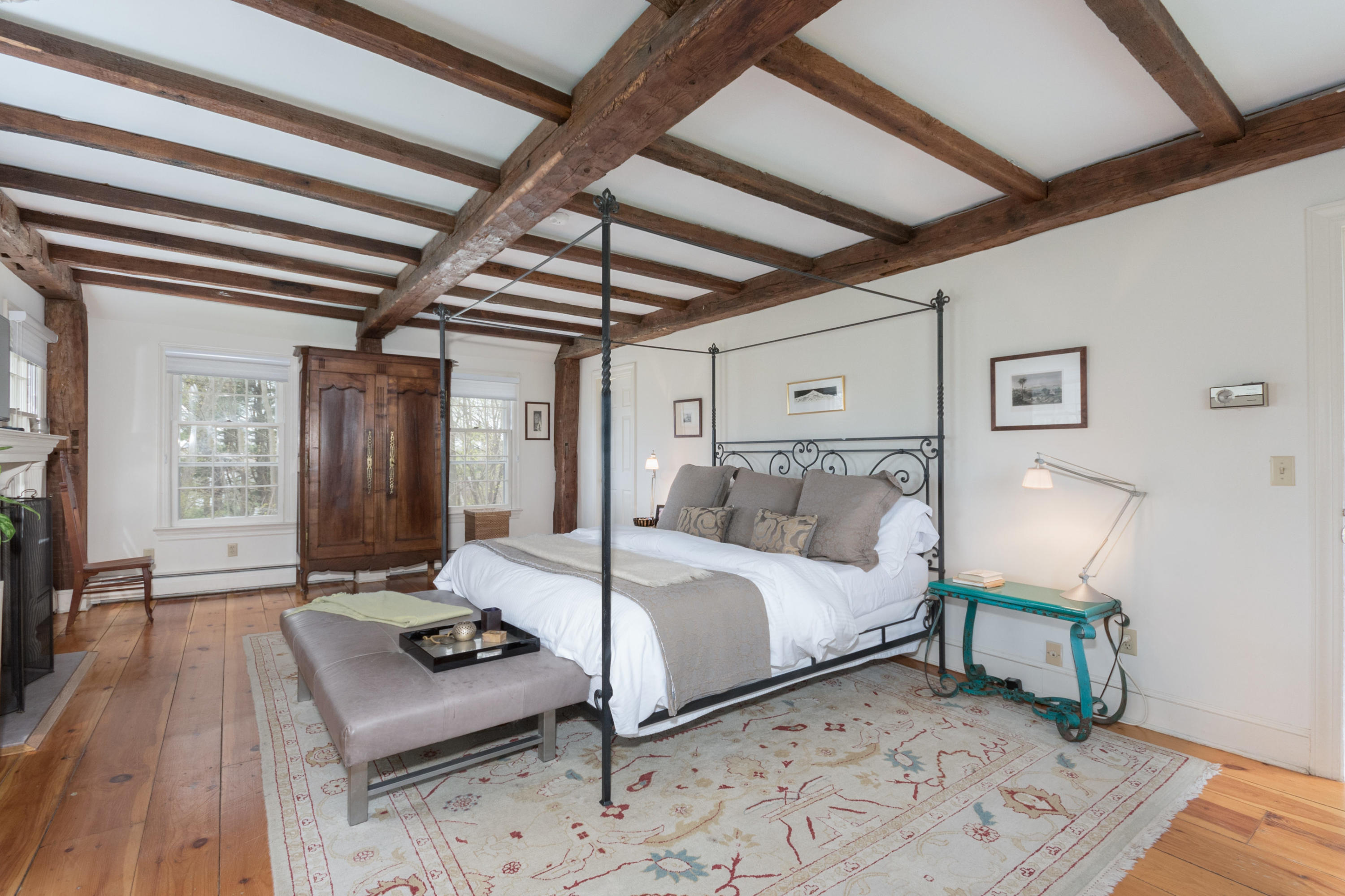 106 Long Neck Point Road Darien, CT 06820 - Photo 23 of 48 a bedroom with a bed a table and wooden floor