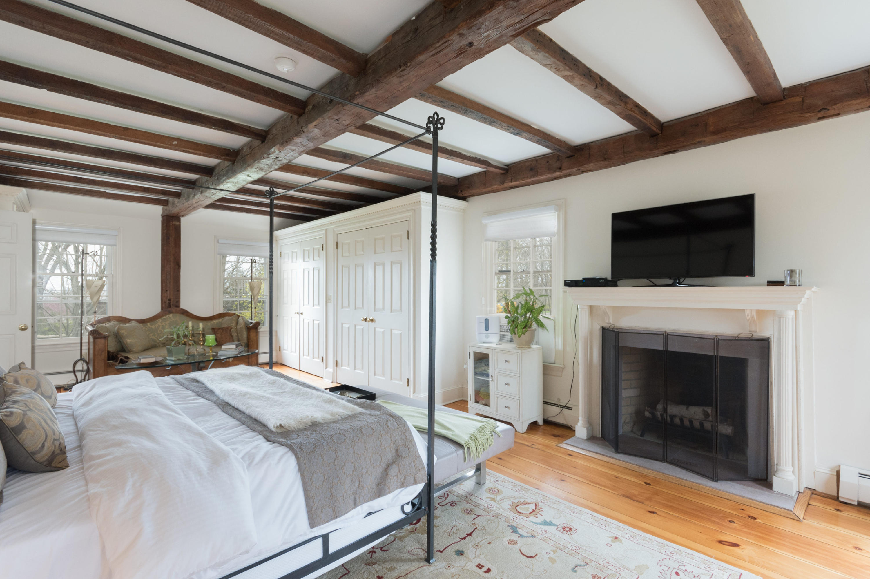 106 Long Neck Point Road Darien, CT 06820 - Photo 25 of 48 a spacious bedroom with a bed and a fireplace with a bookshelf