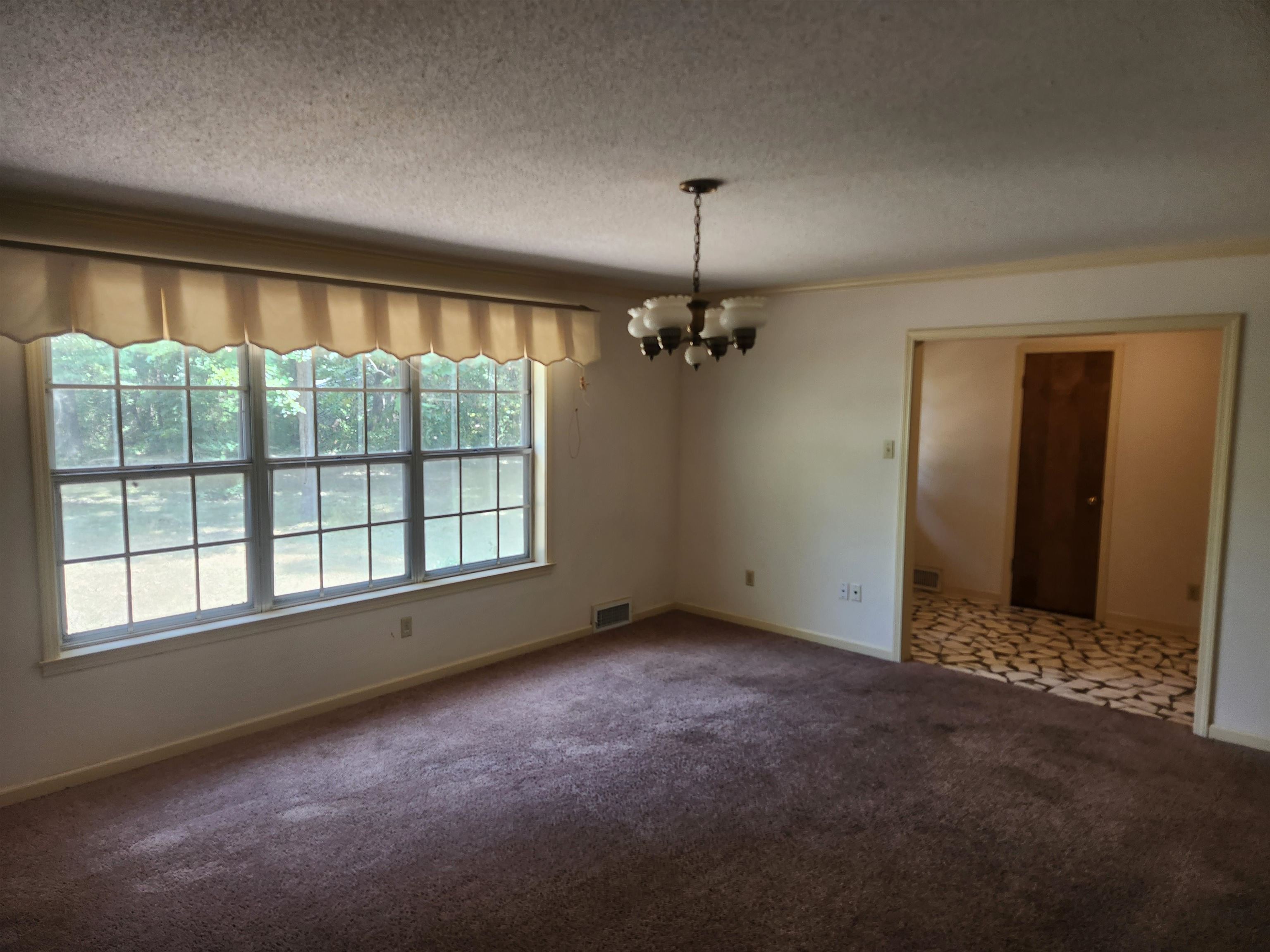 7505 Dexter Road Cordova, TN 38016 - Photo 6 of 27 Carpeted empty room featuring a wealth of natural light, a textured ceiling, and an inviting chandelier