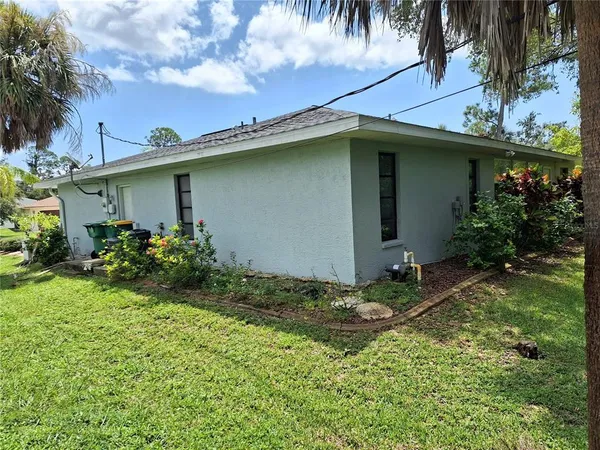 a backyard of a house with plants and palm tree