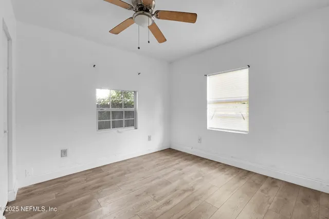 an empty room with a window and a fan