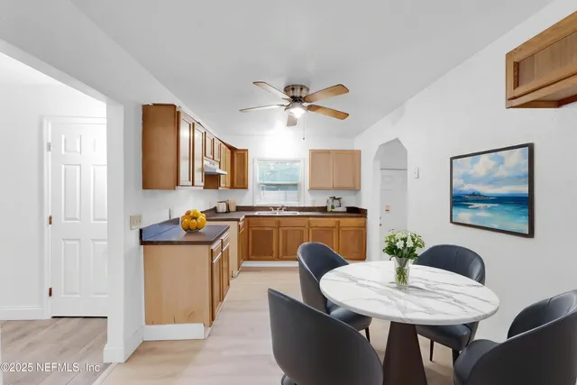 a dining room with stainless steel appliances kitchen island granite countertop a dining table chairs and a refrigerator