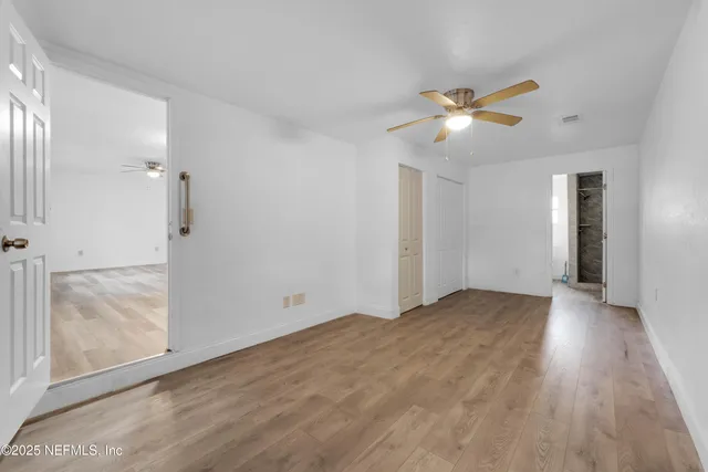 a view of empty room with wooden floor and fan