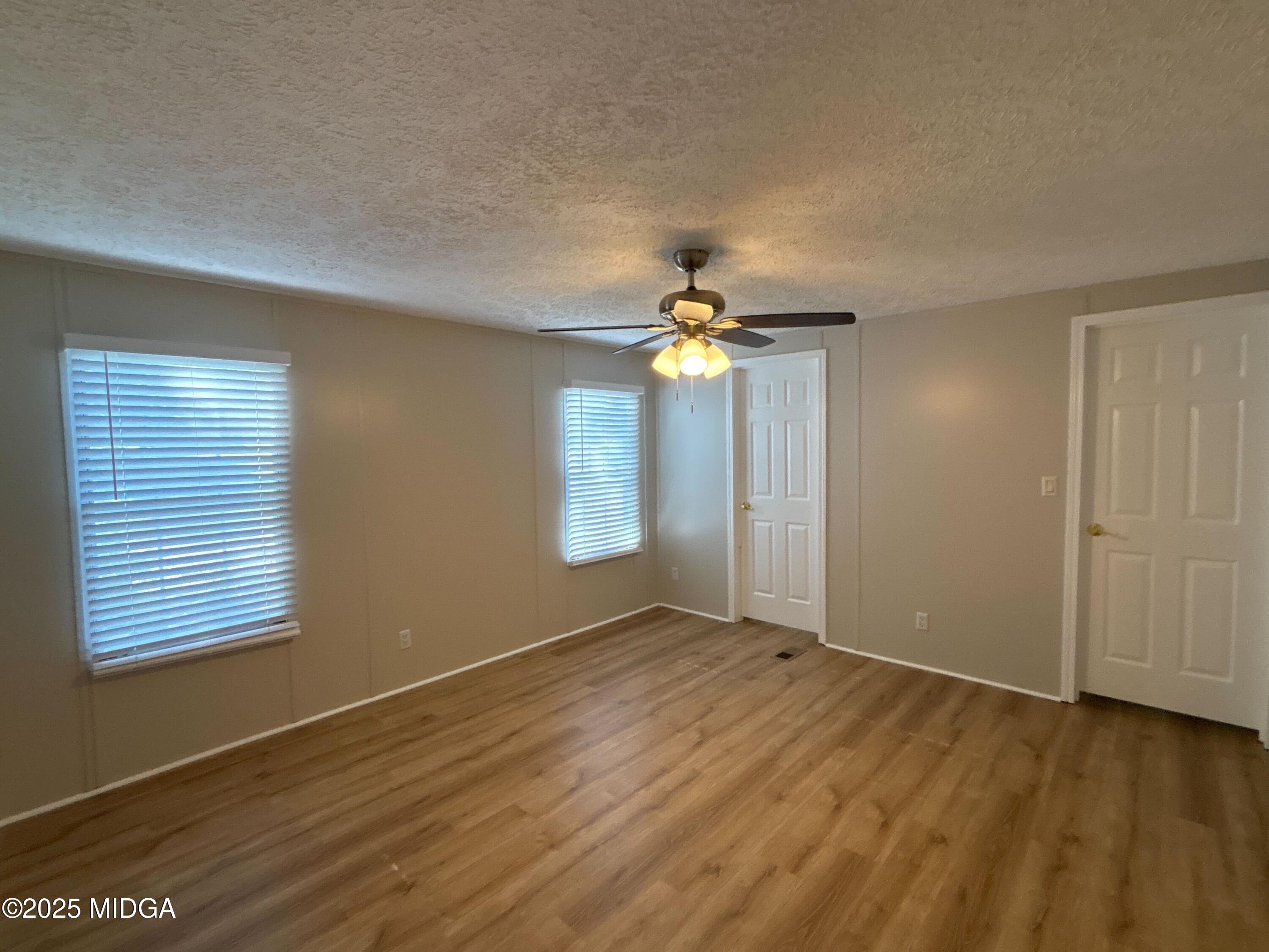 137 Alview Drive Macon, GA 31206 - Photo 9 of 22 an empty room with wooden floor chandelier fan and windows