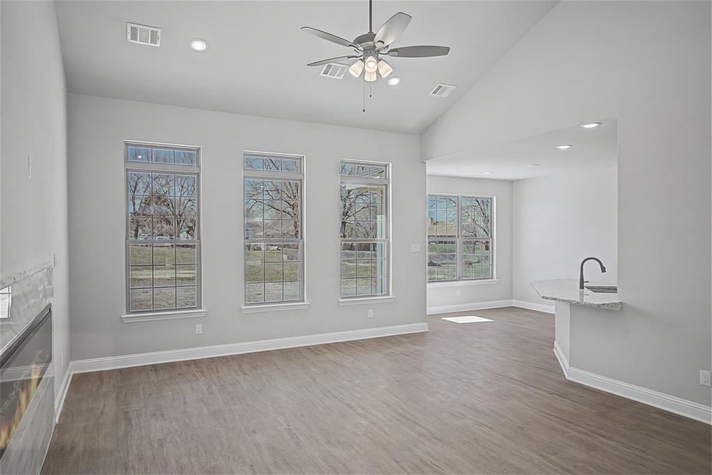 44 Karol Jean Way Quinlan, TX 75474 - Photo 7 of 36 Unfurnished living room featuring light wood-style floors, a ceiling fan, vaulted ceiling, a glass covered fireplace, and recessed lighting