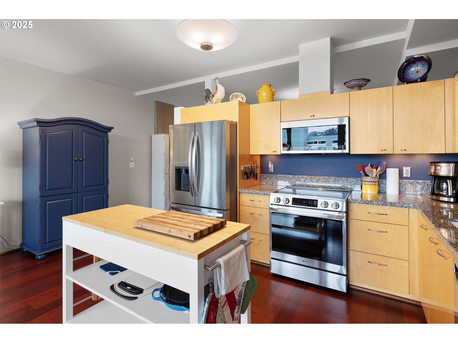 1221 Southwest 10th Avenue, Unit 809 Portland, OR 97205 - Photo 9 of 39 a kitchen with stainless steel appliances kitchen island a table chairs in it and wooden floors