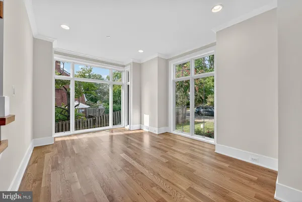 a view of an empty room with wooden floor and windows