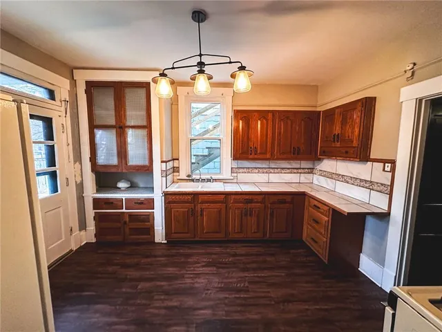 a kitchen with stainless steel appliances kitchen island granite countertop a refrigerator a sink dishwasher a stove and white countertops with wooden floor