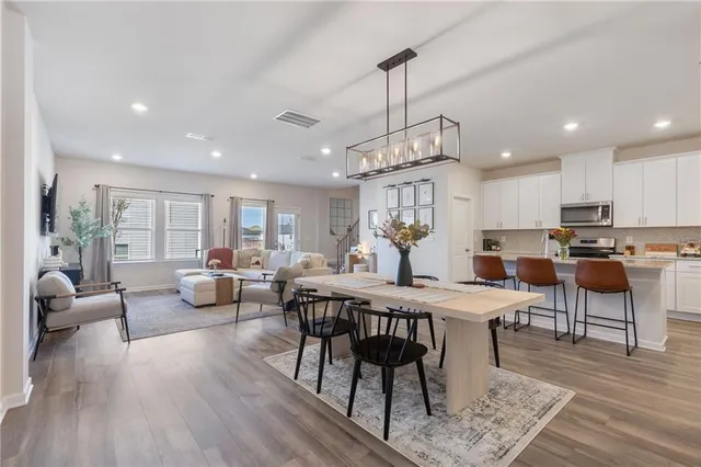 a view of a dining room and livingroom with furniture wooden floor a chandelier
