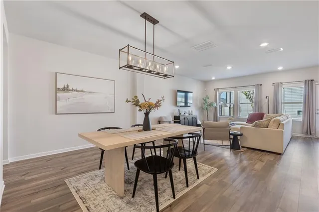 a kitchen with stainless steel appliances granite countertop a stove top oven a sink dishwasher a refrigerator and white cabinets with wooden floor