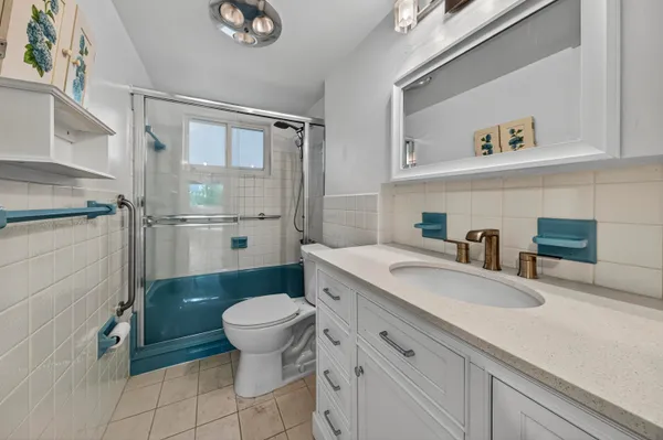 a bathroom with a granite countertop sink a toilet a mirror and shower
