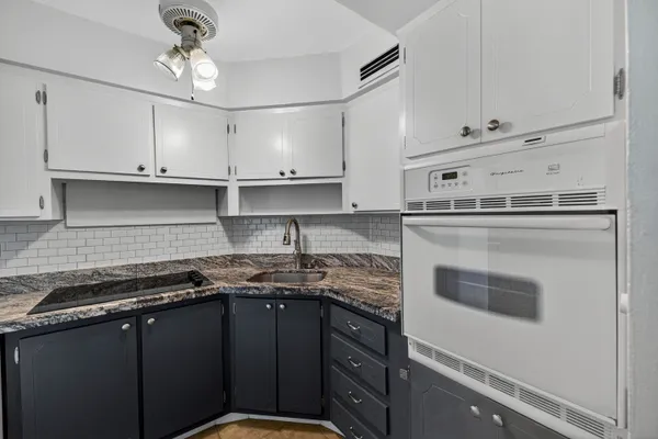 a kitchen with granite countertop a sink a stove and cabinets