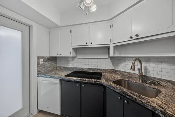 a kitchen with granite countertop a sink stainless steel appliances and cabinets