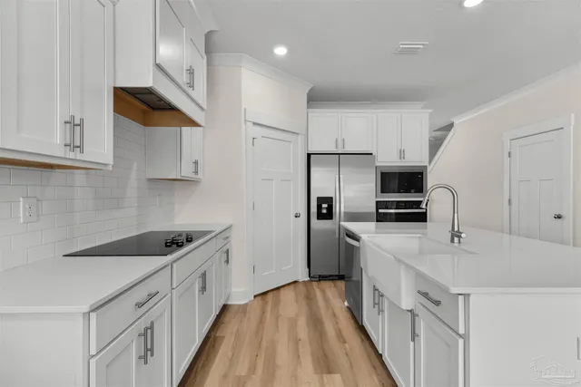 a kitchen with white cabinets sink and stainless steel appliances