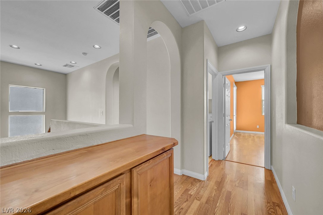 977 Sparkling Light Street Henderson, NV 89052 - Photo 41 of 75 This interior hallway features a harmonious blend of natural wood flooring and architectural arches.
