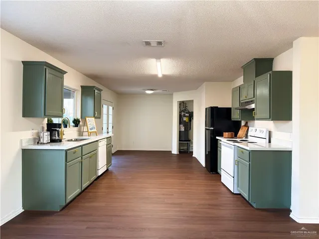 a large kitchen with a sink and a refrigerator