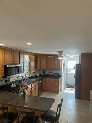 a kitchen with stainless steel appliances granite countertop a refrigerator a stove a sink a dining table and chairs