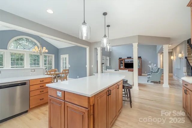 a large kitchen with kitchen island a large island a sink appliances and a large window
