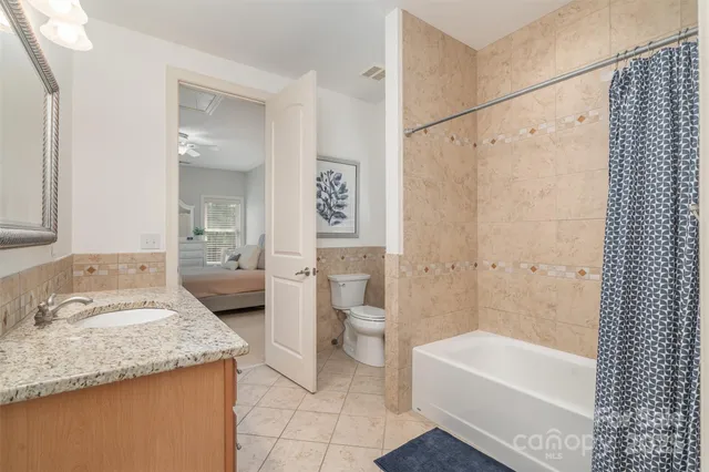 a bathroom with a granite countertop sink a toilet and shower