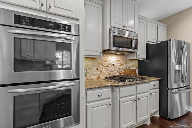 a kitchen with white cabinets and stainless steel appliances