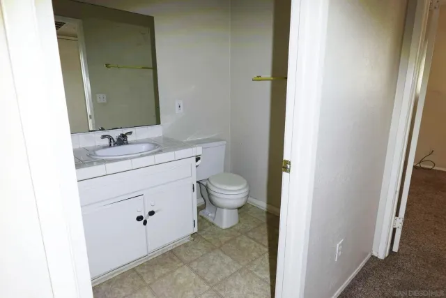 a bathroom with a granite countertop sink toilet and mirror