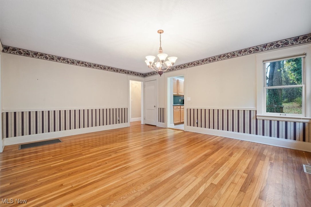 4488 Rainbow Road Cleveland, OH 44121 - Photo 14 of 39 Unfurnished room with wood-type flooring and an inviting chandelier