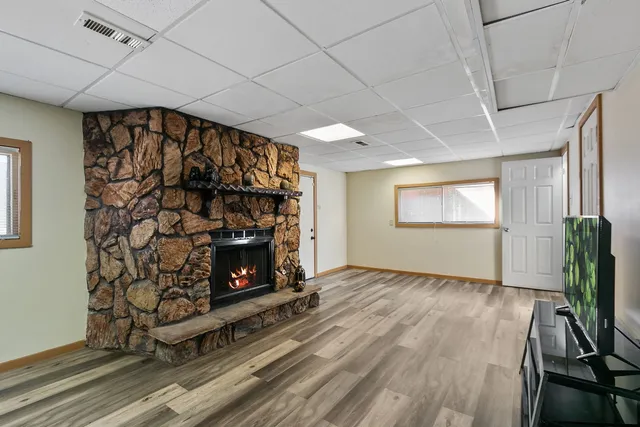 a view of an empty room with wooden floor fireplace and a window