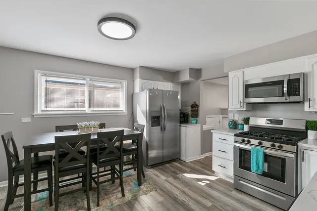 a kitchen with stainless steel appliances a stove a refrigerator and a dining table