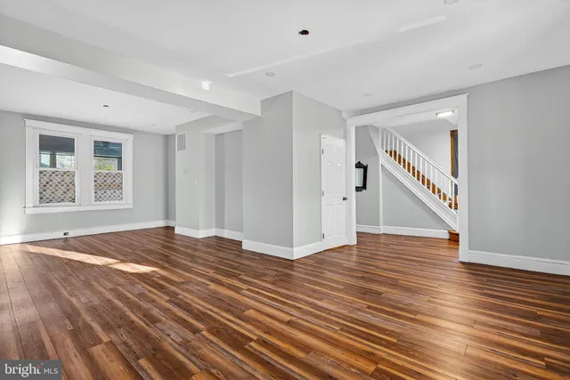 a view of an empty room with wooden floor and stairs