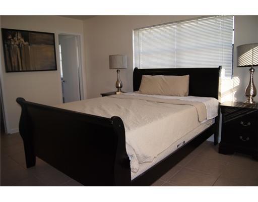 1651 North Cypress Road Pompano Beach, FL 33060 - Photo 5 of 12 a bed sitting in a bedroom and a night stand