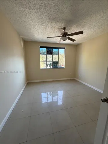 an empty room with windows and ceiling fan
