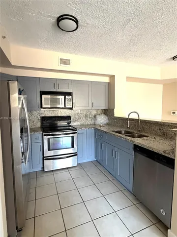 a kitchen with stainless steel appliances granite countertop a sink and a refrigerator
