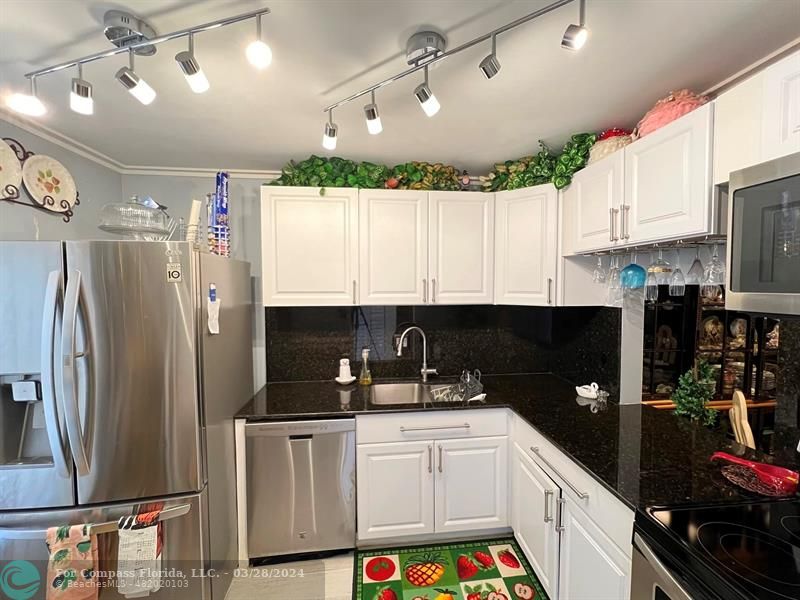 a kitchen with stainless steel appliances granite countertop a refrigerator a sink dishwasher a stove and a refrigerator