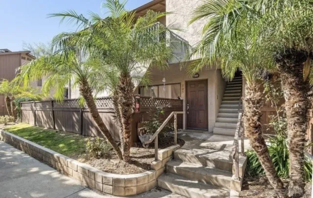 a small yard in front of a house with large tree