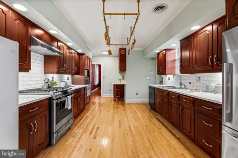 a kitchen with stainless steel appliances granite countertop wooden cabinets a stove top oven a sink and dishwasher