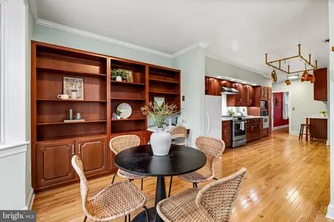 a kitchen with stainless steel appliances granite countertop a table chairs and a living room view