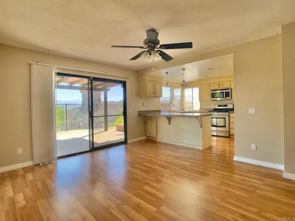 an empty room with wooden floor and a kitchen