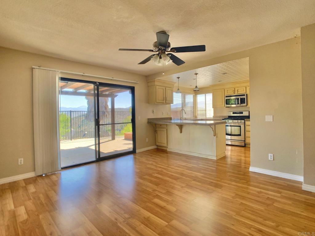 3331 Eton Greens Court Spring Valley, CA 91978 - Photo 12 of 39 an empty room with wooden floor and a kitchen