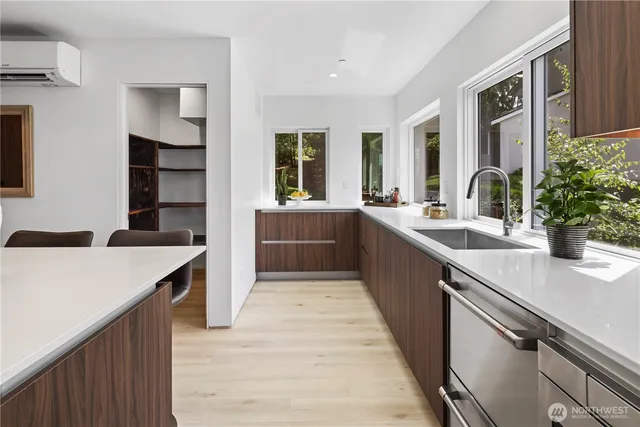 a large kitchen with a large counter top space a sink wooden floor and stainless steel appliances