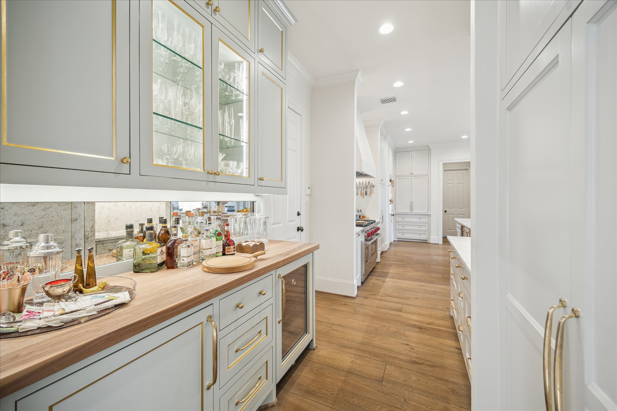 11524 Taylorcrest Road Houston, TX 77024 - Photo 23 of 47 The butler’s pantry offers abundant drawers and cabinetry and leads to a custom bar featuring a walnut butcher block counter with Segreto-painted gold gilt accents, an oxidized mirrored backsplash, and glass-front cabinets for crystal. Additional features include a dual-zone wine refrigerator and a stadium-style liquor storage drawer.