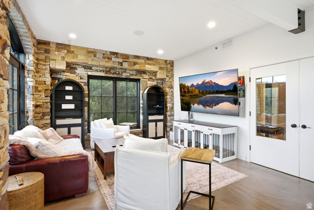 5971 Maple Ridge Trail Oakley, UT 84055 - Photo 20 of 43 Living area featuring a natural stone accent wall with built-in arched shelving, large black-framed windows, and light-tone flooring