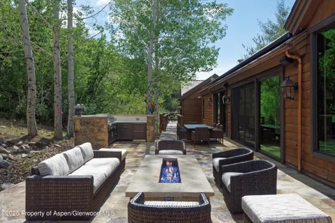 a view of a patio with table and chairs potted plants and floor to ceiling window