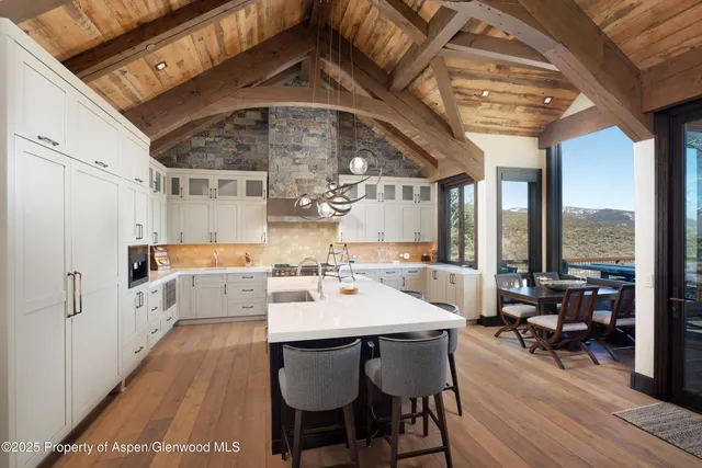 a dining room with wooden floor a chandelier a wooden table and chairs