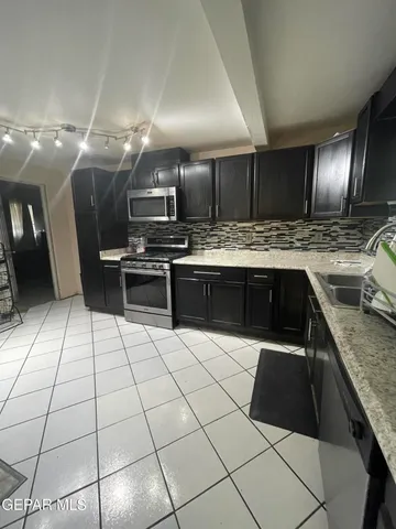 a kitchen with stainless steel appliances kitchen island granite countertop a refrigerator and a sink