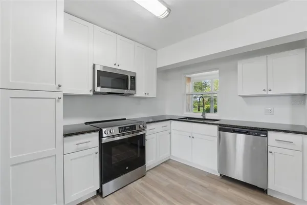 a kitchen with white cabinets stainless steel appliances and a sink