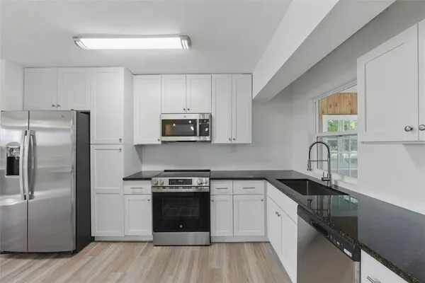 a kitchen with granite countertop a refrigerator and a sink