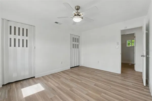 an empty room with windows and ceiling fan