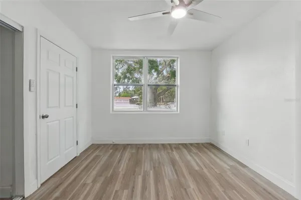 a view of empty room with wooden floor and fan