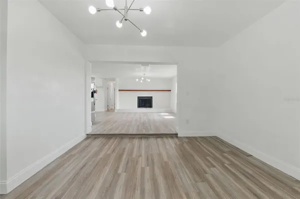 an empty room with wooden floor and chandelier