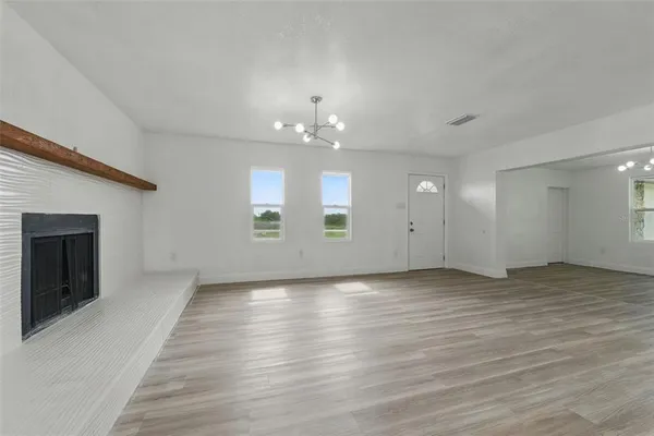 a view of empty room with wooden floor and kitchen view